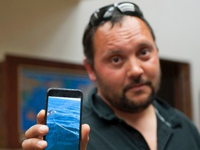 In this Monday, July 24, 2017 photo Victor Littlefield holds up a cellphone video of an orca whale pulling a line off his boat near Sitka, Alaska. Littlefield of Sitka says his boat was attacked by an orca during a fishing excursion with his 14-year-old son and two others. Littlefield says the party was aboard his anchored 33-foot aluminum boat Sunday near Little Biorka Island when it lurched to one side. (James Poulson/The Daily Sitka Sentinel via AP)