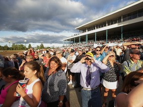 Fans monitor one of the early races at Fort Erie Race Track yesterday before the running of the 82nd Prince of Wales Stakes. (JULIE JOCSAK/Postmedia Network)