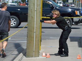 Det. Terri Jackson of London police forensics probes the scene of Tuesday?s stabbing outside Goodwill Industries on Horton Street. Hashim Peters appeared in court on aggravated assault and weapons charges Wednesday. (MORRIS LAMONT, The London Free Press)