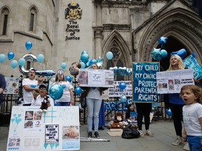 Supporters of critically ill baby Charlie Gard shout and hold placards before his parents Connie Yates and Chris Gard arrived at the High Court in London, Monday, July 24, 2017. (AP Photo/Matt Dunham)