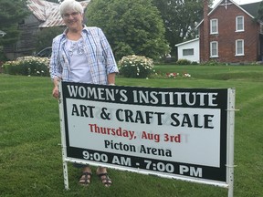 BRUCE BELL/THE INTELLIGENCER
Prince Edward District Women’s Institute president Evelyn Peck is pictured with one of the signs advertising the organization’s 34th annual craft sale on Aug. 3, at the Picton Fairgrounds. The one-day event attracts thousands of visitors and raises approximately $20,000 annually for community initiatives, including accessible transportation in Prince Edward County.