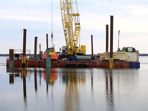 Workers on a barge build a temporary dock near Millhaven as part of the Amherst Island wind project on March 6. (Elliot Ferguson/The Whig-Standard)