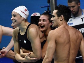 Team Canada's Penny Oleksiak, left, Kylie Masse and Richard Funk celebrate winning the bronze medal in the mixed 4x100 medley final at the 2017 FINA World Championships in Budapest, on July 26, 2017. (AFP PHOTO)