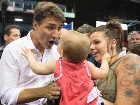 Prime Minister Justin Trudeau reacts as he picks up 13-month-old Laurie Gauthier Chouinard while visiting a local county fair Wednesday, July 26, 2017 in Saguenay, Que. THE CANADIAN PRESS/Jacques Boissinot