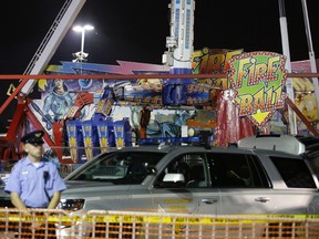 Authorities stand near the Fire Ball amusement ride after the ride malfunctioned injuring several at the Ohio State Fair, Wednesday, July 26, 2017, in Columbus, Ohio. Some of the victims were thrown from the ride when it malfunctioned Wednesday night, said Columbus Fire Battalion Chief Steve Martin. (Barbara J. Perenic/The Columbus Dispatch via AP)