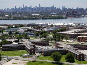 In a June 20, 2014, file photo, the Rikers Island jail complex stands in New York with the Manhattan skyline in the background. New York City's sprawling and troubled Rikers Island jail complex has been put on lockdown while authorities look for a missing inmate. (AP Photo/Seth Wenig, File)