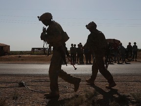 U.S. soldiers (foreground) walk in front of Syrian children at a road that links to Raqqa, Syria, on Wednesday, July 26, 2017. The U.S. has up to 1,000 troops in Syria mostly involved in training and advising the local forces against the Islamic State. (Hussein Malla/AP Photo)