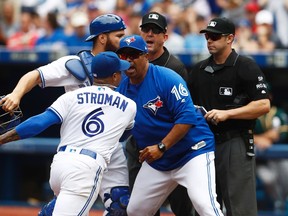 Blue Jays bench coach DeMarlo Hale (16) tries to hold back starting pitcher Marcus Stroman (6) and catcher Russell Martin after they were ejected by umpire Will Little (right) during fifth inning MLB action against the Athletics in Toronto on Thursday, July 27, 2017. (Mark Blinch/The Canadian Press)