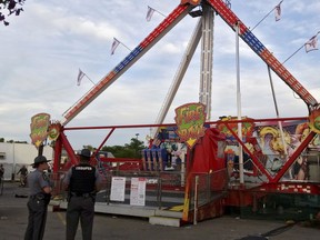 Authorities stand near the Fire Ball amusement ride after the ride malfunctioned injuring several at the Ohio State Fair, Wednesday, July 26, 2017, in Columbus, Ohio. (Jim Woods/The Columbus Dispatch via AP)