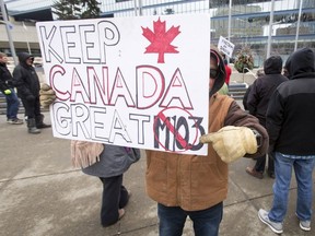 A man hides his face while promoting his anti-Motion 103 sign outside of City Hall in Calgary, on March 4, 2017. Two opposing demonstrations were occurring simultaneously just metres from each other, one supporting Motion 103, which would deem Islamophobia a hate crime, and the other opposing it, saying it would hurt freedom of speech. The House of Commons passed the motion in late-March. (Lyle Aspinall/Postmedia Network)