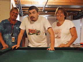 Paula Carson, with UNIFOR, Travis Mayor, and his moth Diane Mayor stand behind the pool table at their Tilbury house. Travis goes to Community Living’s adult respite program in Chatham and thanks to generous donation from the community, has a pool table to play with there as well.