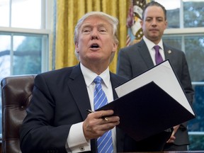 In this file photo, US President Donald Trump signs an executive order alongside White House Chief of Staff Reince Priebus in the Oval Office of the White House in Washington, DC, January 23, 2017. SAUL LOEB/AFP/Getty Images