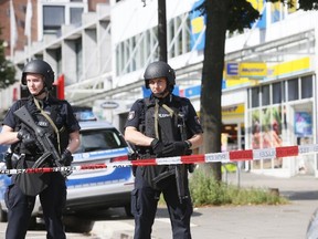 Police officers secure the area after a knife attack at a supermarket in Hamburg, Germany, on Friday, July 28, 2017. (Paul Weidenbaum/dpa via AP)