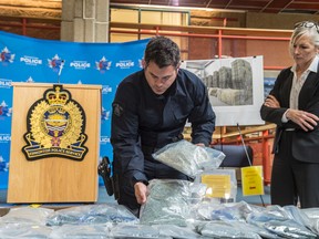 Const. Jason Wells with the RCMP Clandestine Lab Enforcement and Response (CLEAR) Team, left, and Staff Sgt. Karen Ockerman with the Edmonton Drug and Gang Enforcement (EDGE) Unit show on July 28, 2017 an estimated 130,000 fentanyl pills with an approximate street value of $2 million that were seized in a property search on July 5, 2017. Shaughn Butts / Postmedia