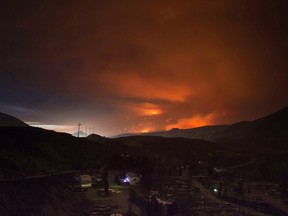 A wildfire burns on a mountain in the distance east of Cache Creek behind a trailer park that was almost completely destroyed by wildfire, in Boston Flats, B.C., in the early morning hours of July 10, 2017. (THE CANADIAN PRESS/Darryl Dyck)