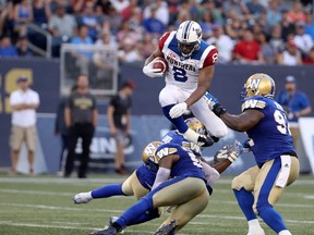 Montreal Alouettes slotback Nik Lewis hurdles Winnipeg Blue Bombers linebacker Kyle Knox and defensive lineman Jamaal Westerman before being tackled by defensive tackle Drake Nevis during CFL action in Winnipeg on July 27, 2017. (THE CANADIAN PRESS/Trevor Hagan)