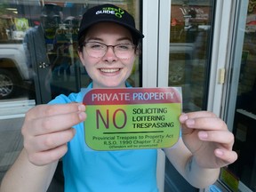 Lauren O?Donnell shows one of the stickers she and other Super Guides working for Downtown London will be passing out to merchants to put on their stores. (MORRIS LAMONT, The London Free Press)