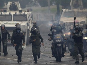 Bolivarian National Guards fire as they advance toward anti-government demonstrators in Caracas, Venezuela, on Friday, July 28, 2017, two days before the vote to begin the rewriting of Venezuela's constitution. (Ariana Cubillos/AP Photo)