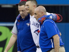 Toronto Blue Jays' Troy Tulowitzki, centre, is helped off the field by trainers Mike Frostad, left, and George Poulis after he injured himself awkwardly running across the first base bag in the third inning of their American League MLB baseball game against the Los Angeles Angels in Toronto on Friday, July 28, 2017. (THE CANADIAN PRESS/Fred Thornhill)