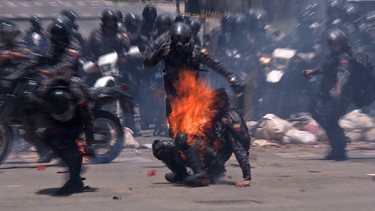 Video grab showing police officers helping a colleague who caught fire after an explosive device went off as they rode past during a protest against the elections for a Constituent Assembly in Caracas on July 30, 2017. LEO RAMIREZ/Getty Images
