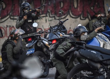 Venezuelan National Guard motorcyclists take cover upon coming under fire during a confuse skirmish in Caracas on July 30, 2017. JUAN BARRETO/Getty Images
