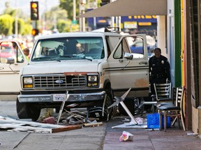 An official looks into a van that plowed into a group of people on a Los Angeles sidewalk on Sunday, July 30, 2017. (AP Photo/Damian Dovarganes)
