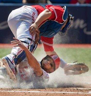 Los Angeles Angels Ben Revere slides through the legs of Toronto Blue Jays catcher Miguel Montero to score on a sacrifice fly in the fifth inning of their AL baseball game in Toronto on Sunday, July 30, 2017. THE CANADIAN PRESS/Fred Thornhill ORG XMIT: FJT11