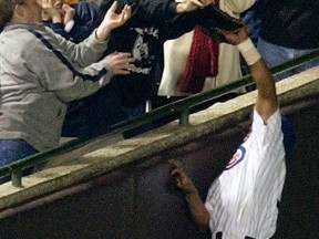 In this Oct. 14, 2003, file photo, Chicago Cubs left fielder Moises Alou reaches into the stands unsuccessfully for a foul ball, as Cubs fan Steve Bartman also reaches for the ball, during the eighth inning during Game 6 of the National League championship series against the Florida Marlins at Wrigley Field in Chicago. Cubs manager Joe Maddon's young team has the chance to chart a new course for the Cubs when they play the Pirates at Pittsburgh on Wednesday, Oct. 7, 2015, in the wild-card game. (AP Photo/Amy Sancetta, File)