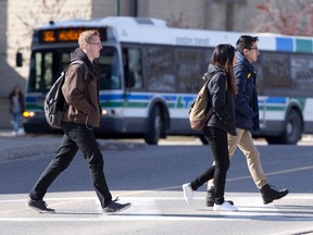 Pedestrians use a crosswalk as a bus pulls up to a stop at Alumni Hall on the Western University campus in London, Ont. on Tuesday February 23, 2016. (Free Press file photo)