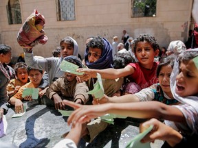 In this April 13, 2017, file photo, Yemenis present documents in order to receive food rations provided by a local charity, in Sanaa, Yemen. Eight of the largest U.S.-based aid groups are joining together in a new campaign to address what the United Nations calls the world's largest humanitarian crisis in more than 70 years. More than 20 million people are at risk of famine in nine African nations and Yemen, but Richard Stearns, president of Federal Way, Washington-based World Vision, says it has been overshadowed amid the controversies surrounding President Donald Trump's administration. (AP Photo/Hani Mohammed, File)