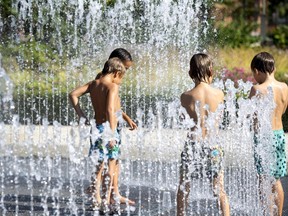 Kids play in a fountain on a hot summer day.