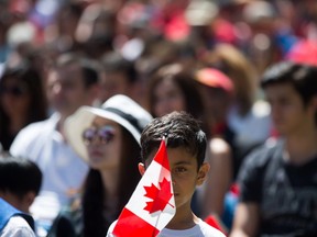 A young boy holds a Canadian flag while watching a special Canada Day citizenship ceremony in West Vancouver, B.C., on Saturday, July 1, 2017. THE CANADIAN PRESS/Darryl Dyck