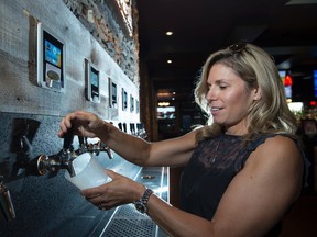 Heather Seale pours herself a Beaver Tail Raspberry Ale from Canmore at Alberta's first self-serve beer and wine wall in the Leduc location of Barney's Pub and Grill on August 2, 2017. Shaughn Butts / Postmedia