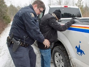 A refugee claimant from Eritrea is frisked and arrested after crossing the border from New York into Canada on March 2, 2017 in Hemmingford, Quebec. (Ryan Remiorz/The Canadian Press)