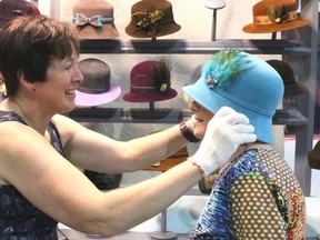 Bruce Bell photographs/The Intelligencer
Picton’s Elizabeth Lythgoe of Class Act Hats gives Shirley McGowan a hand trying on a new hat at the annual Prince Edward County Women’s Institute Arts and Craft Sale at the Picton Fairgrounds on Thursday.