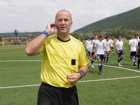 In this July 11, 2017, still image from video, MLS referee Silviu Petrescu tests an earpiece and mic used to communicate with a video assistant referee during a video replay scrimmage organized in a community park, in Park City, Utah. Games were staged as part of the final training camp to gauge MLS referees' competence in and comfort with video replay. (AP Photo/Rick Bowmer)