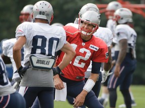 New England Patriots quarterback Tom Brady (12), center right, speaks with wide receiver Danny Amendola (80) while warming up with teammates at NFL football training camp, Thursday, Aug. 3, 2017, in Foxborough, Mass. Brady turned 40-years-old Thursday. (AP Photo/Steven Senne)