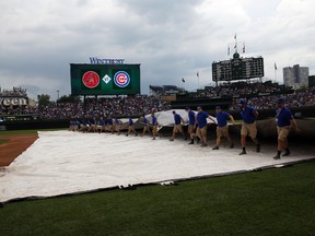 Chicago Cubs grounds crew cover the field during a rain delay before a baseball game between the Cubs and the Arizona Diamondbacks, Thursday, Aug. 3, 2017, in Chicago. (AP Photo/Nam Y. Huh)