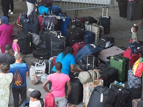 Asylum seekers line up to enter Olympic Stadium Friday, Aug. 4, 2017 near Montreal.  THE CANADIAN PRESS/Paul Chiasson