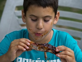Seven-year-old Juan Camilo digs in during the lunch hour at London Ribfest in Victorias Park Friday. (DEREK RUTTAN, The London Free Press)