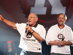Former Ottawa Rough Riders football player Tony Gabriel, right, and Russ Jackson celebrate on stage after the new logo and name, the RedBlacks, are announced for the new Ottawa CFL franchise in Ottawa on June 8, 2013. (THE CANADIAN PRESS/Patrick Doyle)