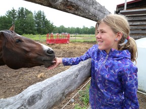 Katie Calvank, 11, is greeted by cricket the horse at Whinnying in Life in Hanmer, Ont. John Lappa/Sudbury Star/Postmedia Network