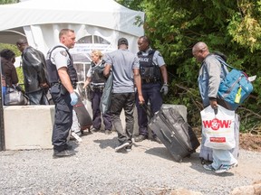 A group of asylum seekers cross the Canadian border at Champlain, N.Y., Friday, August 4, 2017. Prime Minister Justin Trudeau, long an outspoken champion of Canada's reputation for welcoming newcomers, added a bracing dose of reality Friday as he urged would-be migrants to respect the country's border with the United States. THE CANADIAN PRESS/Ryan Remiorz