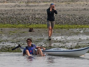 A Parks Canada staff member, back, reacts after Prime Minister Justin Trudeau fell into the water while trying to get into a kayak at Sidney Spit in the Gulf Islands National Park Reserve, east of Sidney, B.C., on Saturday August 5, 2017. THE CANADIAN PRESS/Darryl Dyck