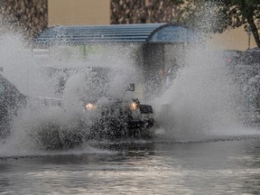 Heavy rain and small hail clogged the parking lot drain in front of Walmart in Capitano Mall on August 5, 2017.  The spray from a truck and a Jeep caused them to collide in the big puddle. Photo by Shaughn Butts / Postmedia