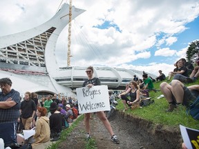 People hold up signs in support of asylum seekers during a rally outside the Olympic Stadium in Montreal, Sunday, August 6, 2017. THE CANADIAN PRESS/Graham Hughes