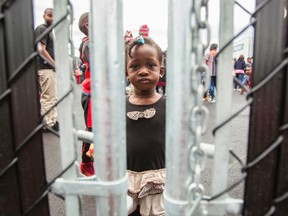 A girl who crossed the Canada/US border illegally with her family, claiming refugee status in Canada, looks through a fence at a temporary detention centre in Blackpool, Quebec, August 5, 2017. (GEOFF ROBINS/Getty Images)