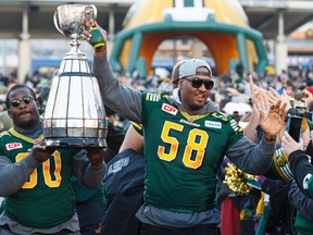 Eskimos' Almondo Sewell (90) and Tony Washington (58) carry the Grey Cup into an Edmonton Eskimos Fan Rally for the Grey Cup champions at Churchill Square in Edmonton, Alta., on Tuesday December 1, 2015. The Eskimos released Washington on Monday.