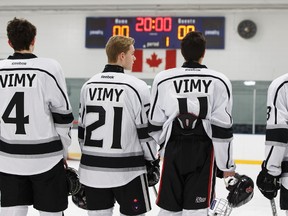 Vimy Ridge Academy hockey players stand for the national anthem during a school hockey game between teachers and students at Kenilworth Arena in Edmonton, Alberta on Friday, December 23, 2016.