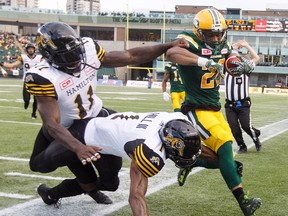 Hamilton Tiger-Cats' Larry Dean (11) and Will Hill (1) run Edmonton Eskimos' LaDarius Perkins (22) out of bounds during first half CFL action in Edmonton, Alta., on Friday August 4, 2017.